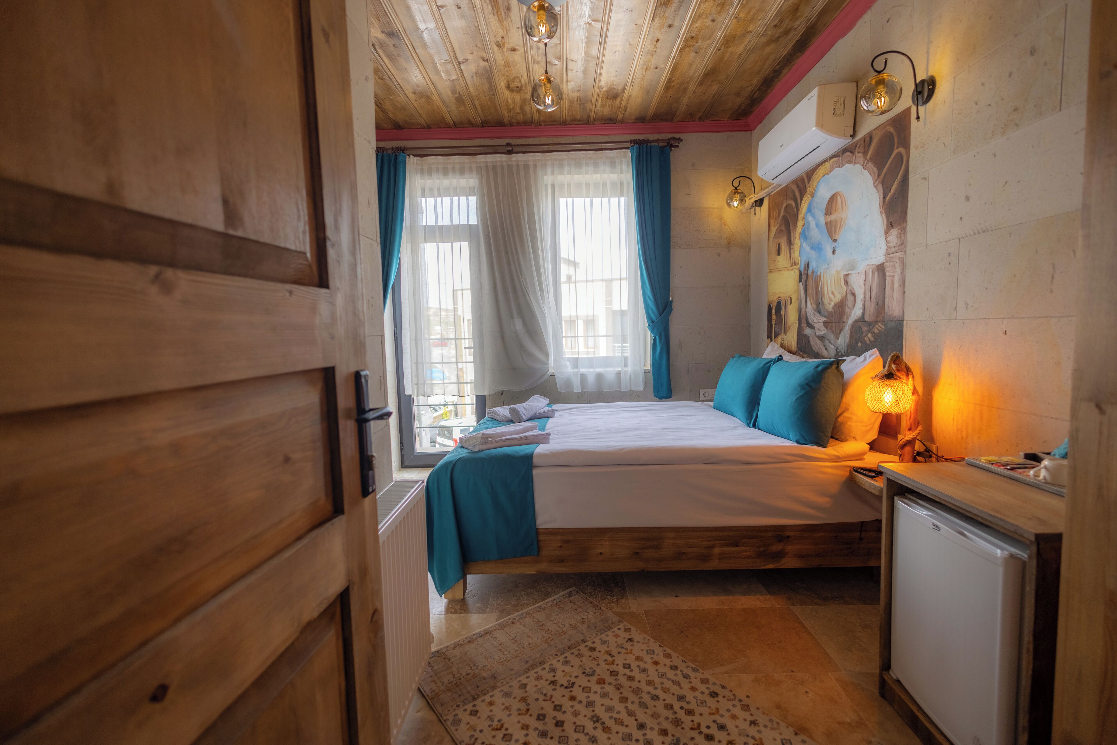 A wooden room with a bed, a small desk, and a wall-mounted air conditioner.