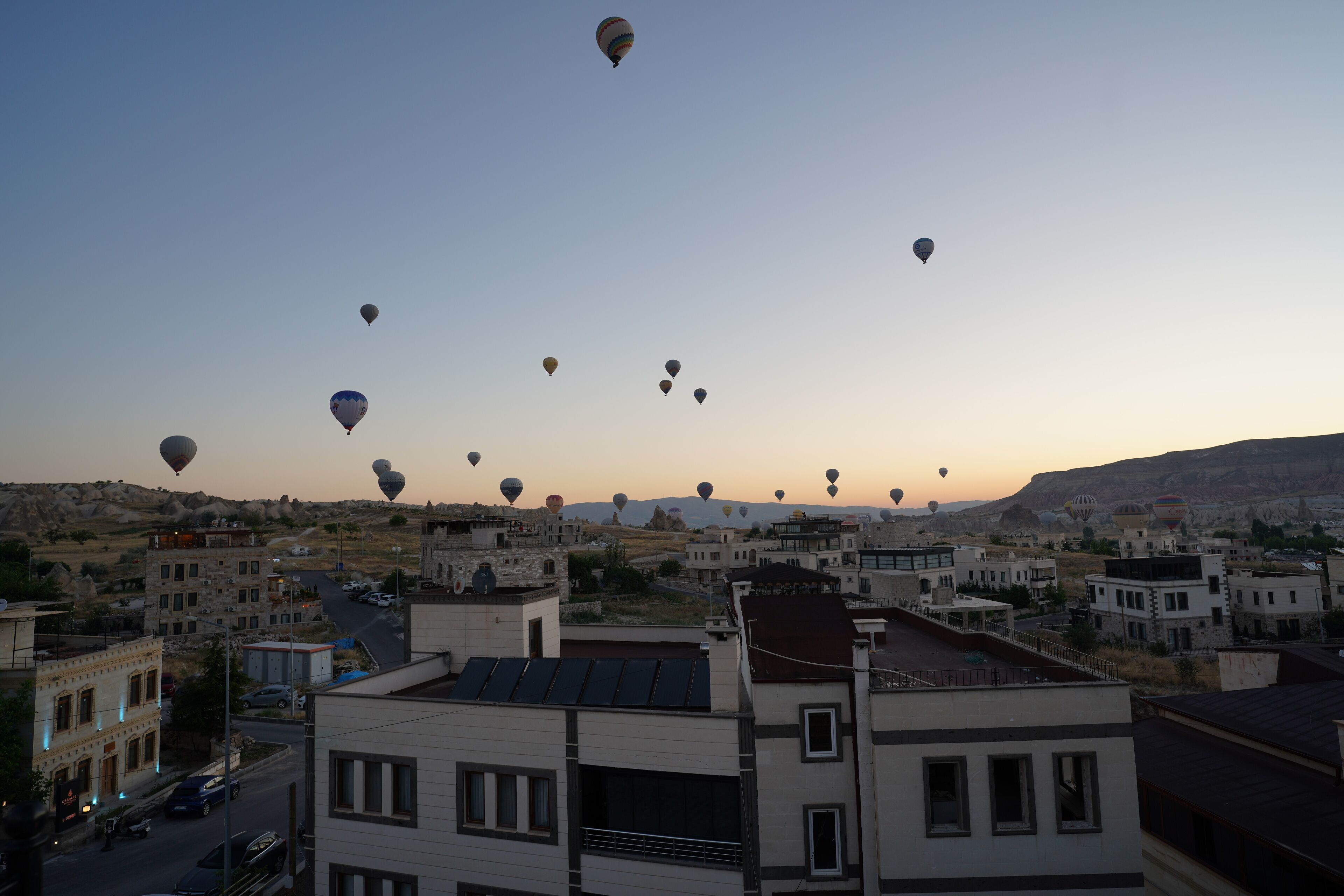 Un paisaje urbano con varios globos aerostáticos en el cielo.