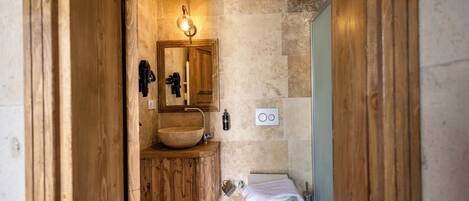 A bathroom with a wooden vanity, a large mirror, a vessel sink, and a toilet.