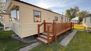 Una casa móvil con una terraza de madera y escalones que llevan a la entrada.
