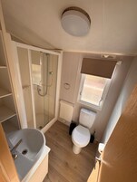 A compact bathroom with a shower, toilet, and sink.