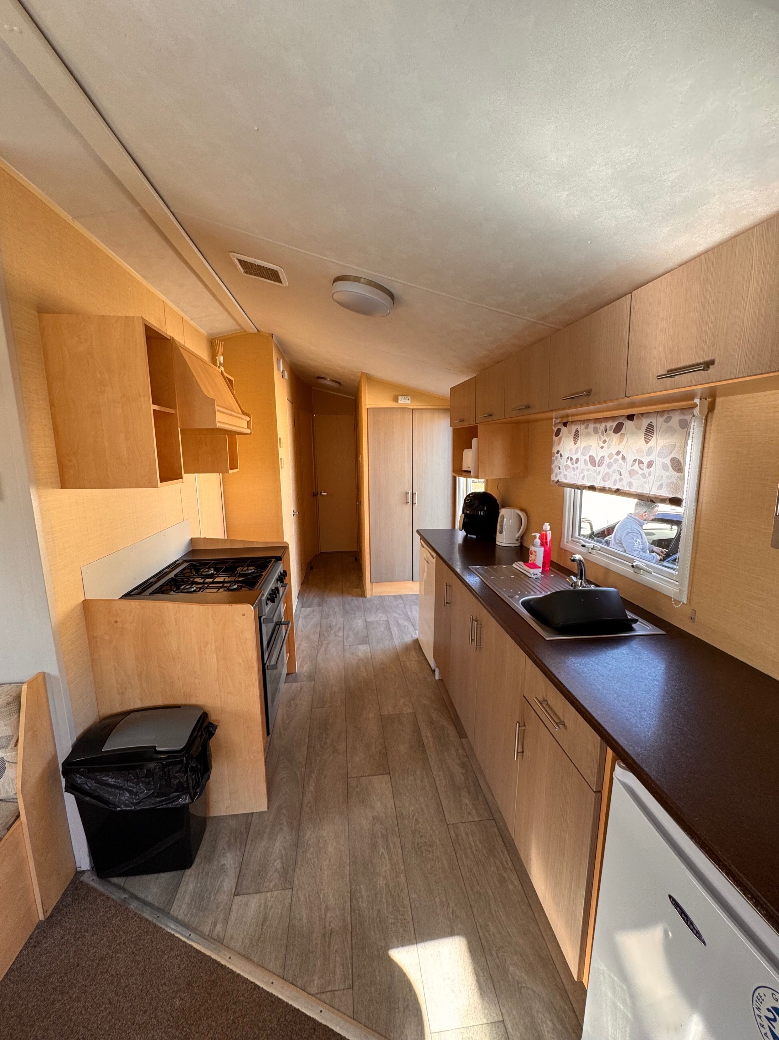 Una cocina compacta con armarios de madera, una estufa y un fregadero.