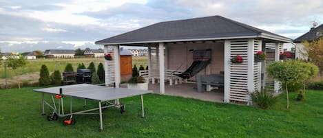 A covered outdoor area with a table, chairs, and a slide.