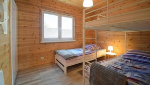 A room with wooden walls, a bunk bed, a window, and a single bed. - Holiday homes close to the beach, large playground (Sarbinowo)