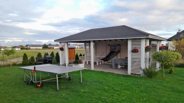 A covered outdoor area with a table, chairs, and a slide. - Holiday homes close to the beach, large playground (Sarbinowo)