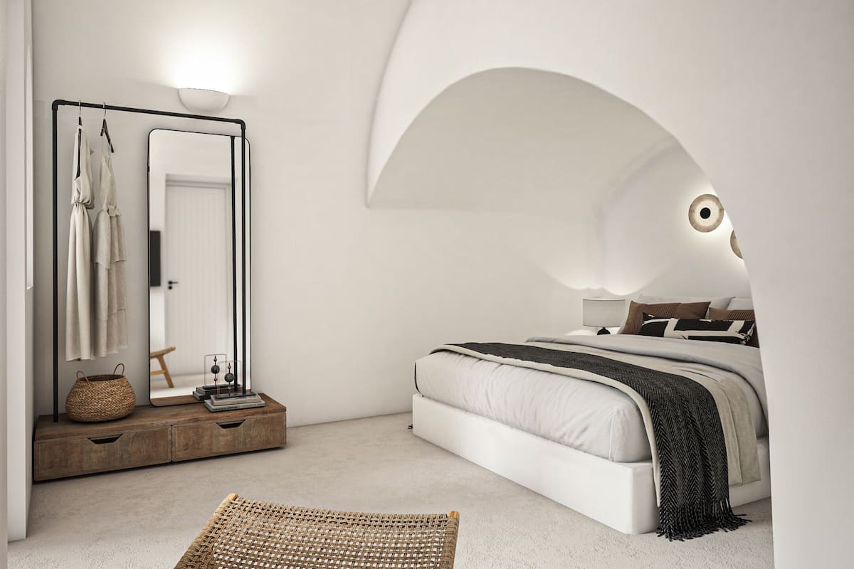 A bedroom with a bed, a mirror, a bedside table, and a wall arch.