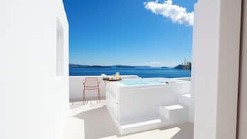 Ein weißer Außenbereich mit Whirlpool, einem Stuhl und Blick auf das Meer.