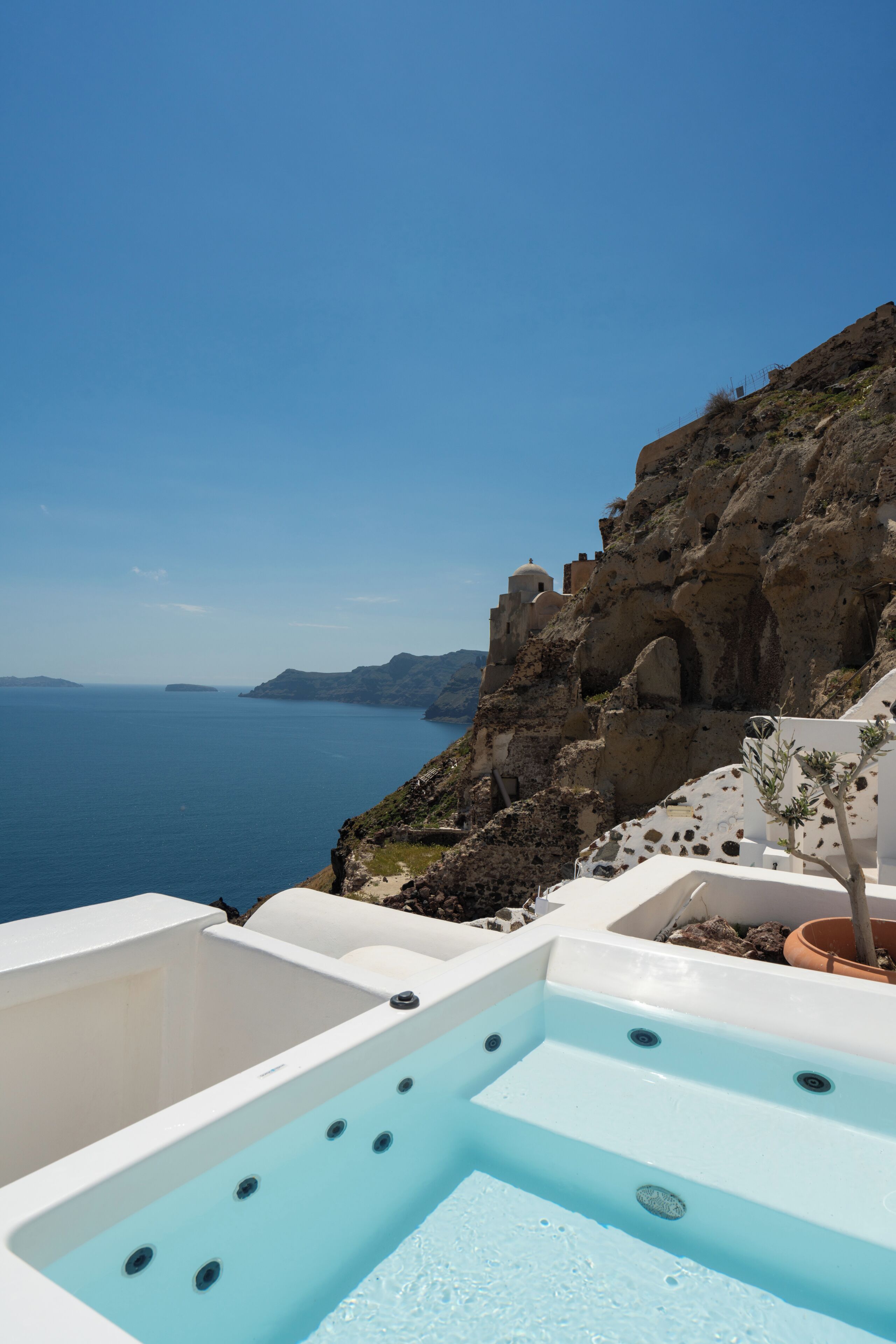 A hot tub with a clear view of the sea and rocky cliffs.