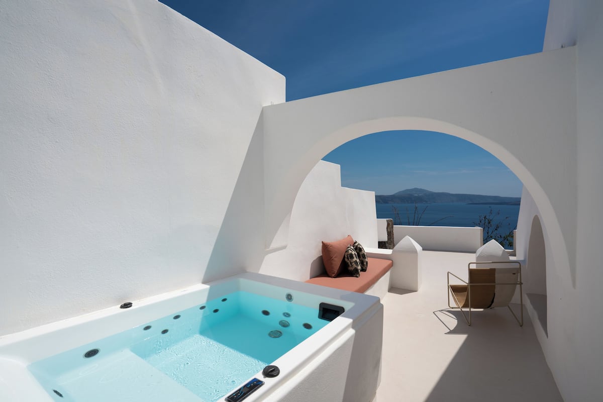 A rooftop terrace with a hot tub, seating area, and a view of the sea.