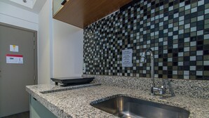 A kitchen with a granite countertop, stainless steel sink, and a checkered backsplash. - Cozy Studio in Sao Paulo Sp-a713 (Sao Caetano do Sul)