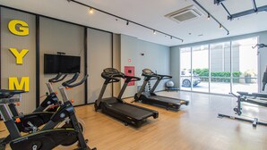 A gym with treadmills, stationary bikes, and a television on the wall. - Cozy Studio in Sao Paulo Sp-a713 (Sao Caetano do Sul)