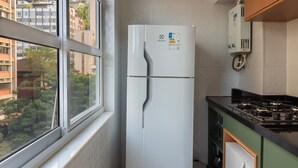 Eine kompakte Küche mit Einbaukühlschrank, Herd und Fenster mit Blick auf die Stadtlandschaft.