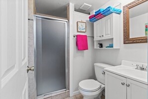 Ein Badezimmer mit Dusche, Toilette, Waschbecken und Spiegel.