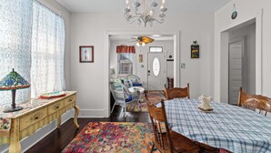 Un coin repas avec une table dressée pour quatre personnes, un lustre et un tapis aux couleurs vives.