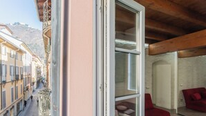 A balcony with a view of a cobblestone street and buildings, a red sofa, and a dining table with chairs. - Domus 2 in Como by Rent All Como (Como)