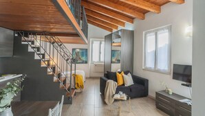 A modern living room with a staircase, a sofa, a TV, and a dining area. - Domus 4 in Como by Rent All Como (Como)