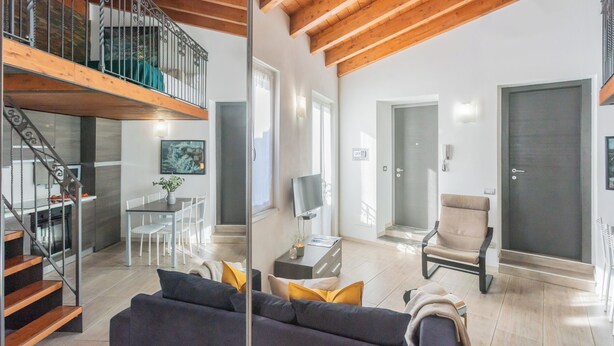 A modern living room with a staircase, a dining area, and a large door.