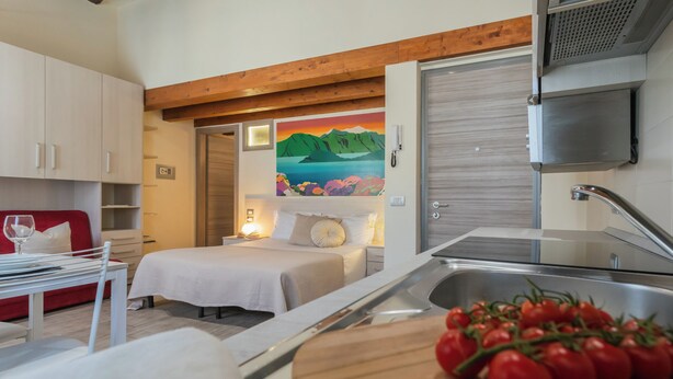 A compact hotel room with a bed, bedside table, and a small kitchenette. - Domus 3 in Como by Rent All Como (Como)