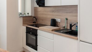 Una cucina moderna con mobili bianchi, un piano di lavoro in legno, un fornello nero e un lampadario.