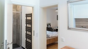 Un bagno moderno con doccia, asciugamano in legno e specchio.