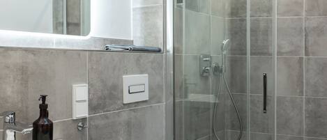 A modern bathroom with a glass-enclosed shower, a white sink, and a toilet.