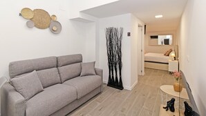 Un salon moderne avec un canapé gris, un élément décoratif mural et une grande sculpture noire.