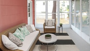 Une pièce avec un canapé en osier, un fauteuil, une petite table sur laquelle est posée une plante, et un ventilateur de plafond.