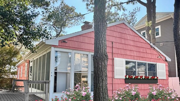 Une maison rouge avec une grande fenêtre et une jardinière devant.