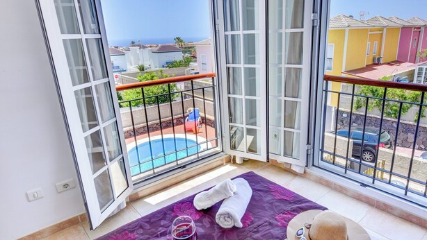 A balcony with a pool view, towels, and a hat.