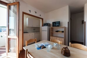 A compact kitchen with a dining table, chairs, a refrigerator, a microwave, and a television.