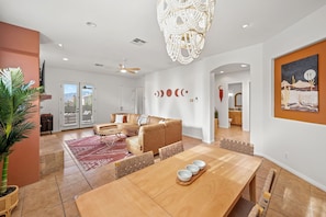 A spacious living area with a wooden dining table, a beige sofa, and a ceiling fan.