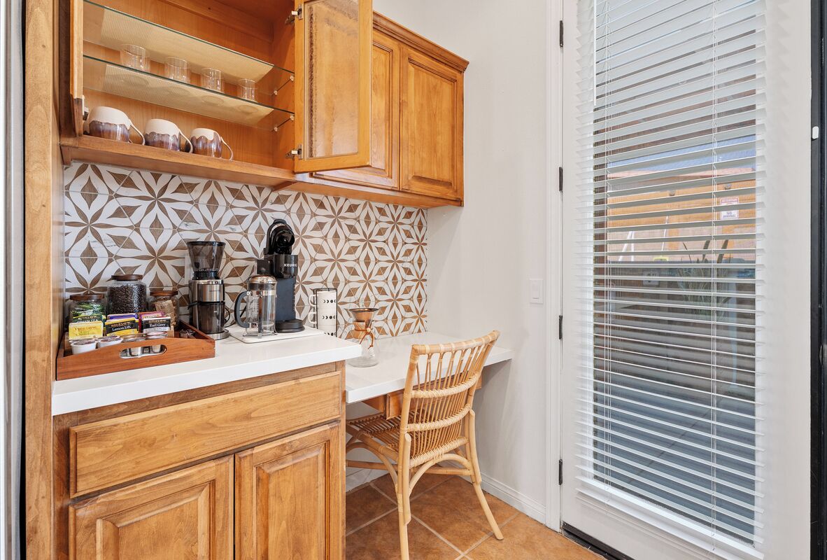 A kitchen with wooden cabinets, a white countertop, and a patterned backsplash.