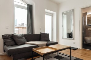 A modern living room with a grey sofa, a wooden coffee table, and a large mirror on the wall. - Vaulted apartment with terrace in Dresden Neustadt Your stylish temporary home (Dresden)