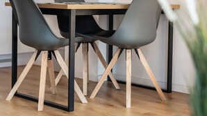 Un'area pranzo con un tavolo in legno e quattro sedie, una stampa botanica incorniciata al muro e una pianta in vaso sullo sfondo.