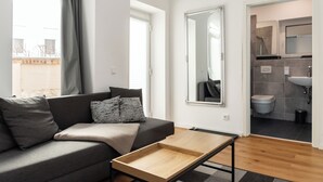 Un soggiorno moderno con un divano grigio, un tavolino in legno e vista sull'esterno tramite ampie finestre.