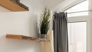 Una camera da letto con un letto, una finestra con tende e una pianta su uno scaffale.