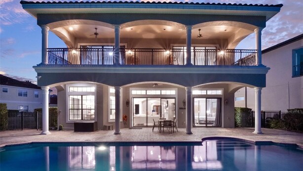 A two-story house with a swimming pool, large windows, and a covered patio.