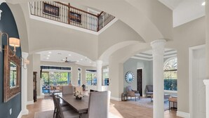 A spacious dining area with a high ceiling and a view of the outdoors.