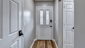 A hallway with white doors, one with a glass panel, and a wooden floor. - "Porchlight Stay" Single story duplex. Dine in downtown Alpharetta/shop Avalon (Alpharetta)