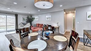 A modern dining area with a round table, chairs, and a hanging light fixture. - "Porchlight Stay" Single story duplex. Dine in downtown Alpharetta/shop Avalon (Alpharetta)