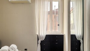 A hotel room with a bed, a black dresser, and a window with sheer curtains. - JOIVY Flat near Milan Centro Storico (Milan)