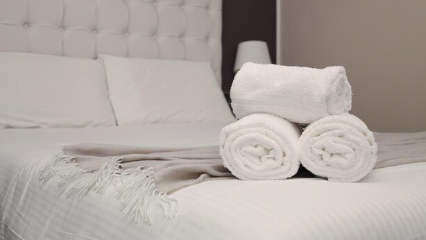 A neatly made bed with rolled white towels and a beige throw blanket. - JOIVY Flat near Milan Centro Storico (Milan)