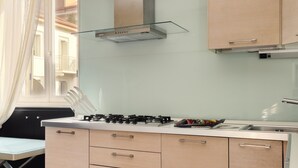 A modern kitchen with a gas stove, a glass range hood, and light-colored cabinets. - JOIVY Flat near Milan Centro Storico (Milan)