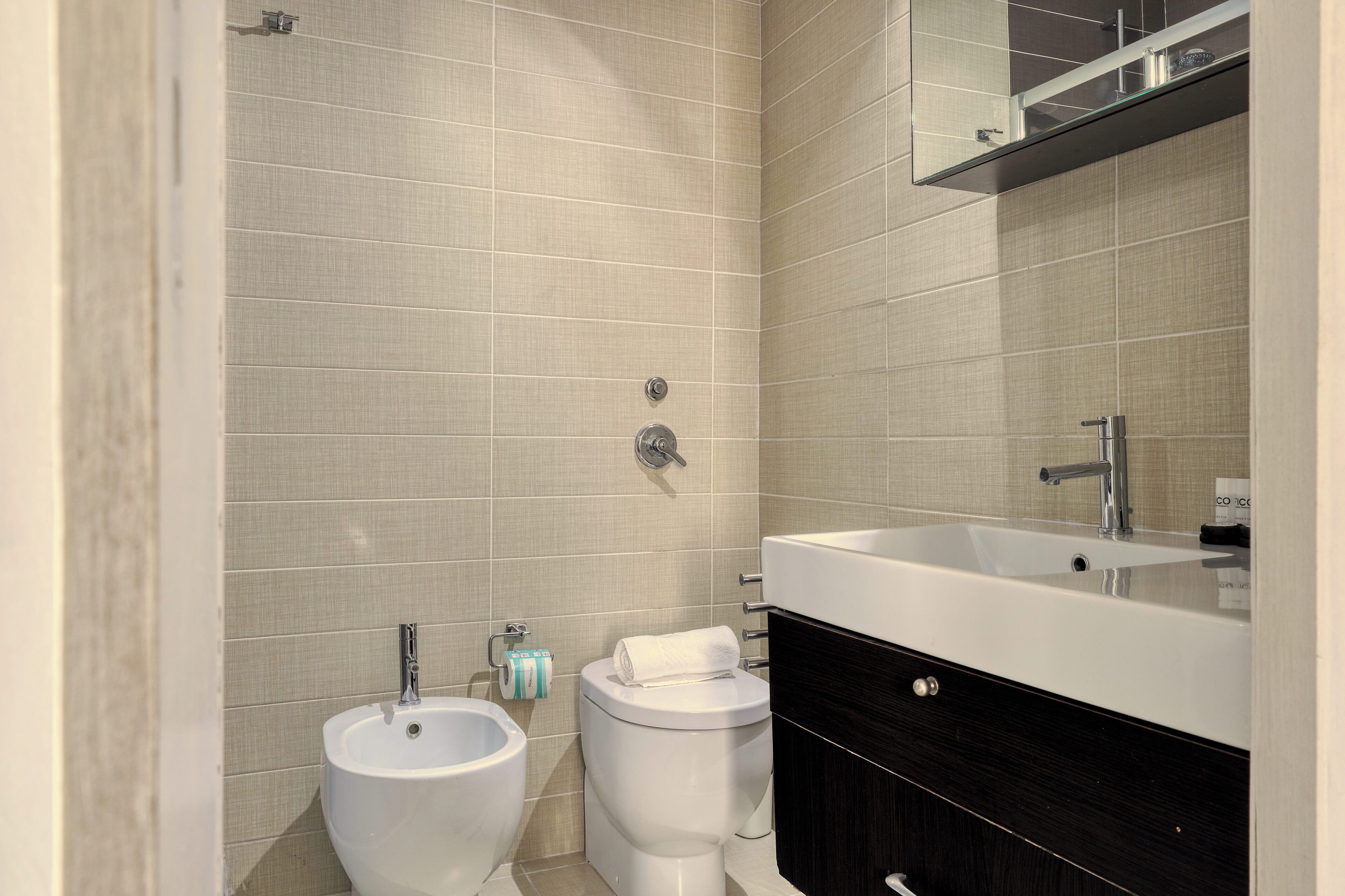 A modern bathroom with a large sink, a bidet, and a toilet.