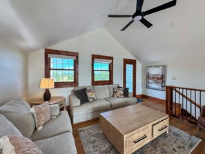 A living room with a sofa set, a coffee table, a lamp, and a ceiling fan.