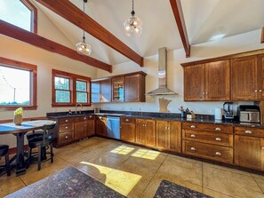 Una cocina con armarios de madera, un lavamanos y un comedor con mesa y sillas.