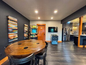 A modern kitchen with dark wood flooring, a large wooden dining table, and a built-in oven.