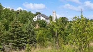 Una casa grande rodeada de un bosque frondoso y una torre de agua.