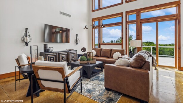 Un salón espacioso con un televisor grande, asientos cómodos y vistas al exterior.