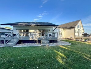 A two-story house with a covered patio, a staircase, and a well-maintained lawn.